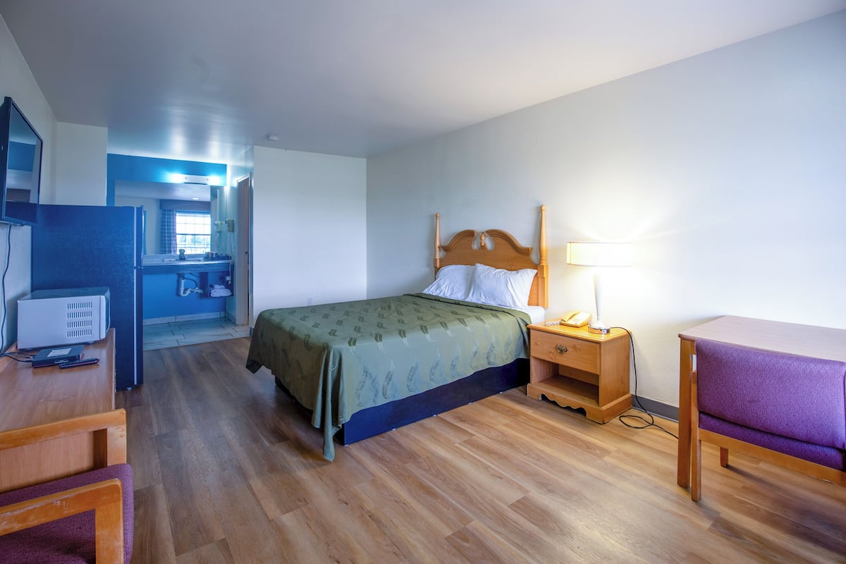 Une pièce comprenant un lit, un bureau, une chaise, une table de chevet, une lampe et une petite table.