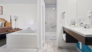 A modern bathroom with a bathtub, shower, and vanity. - Economy Inn & Suites (Rantoul)
