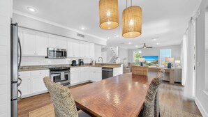 Una cocina moderna con armarios blancos, electrodomésticos de acero inoxidable y una mesa de comedor de madera.