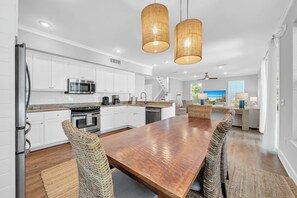 Una cocina moderna con armarios blancos, electrodomésticos de acero inoxidable y una mesa de comedor de madera.