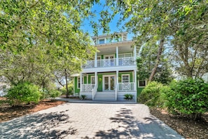 A two-story building with a balcony, surrounded by trees and a paved walkway. - Mojito House with Private Pool, Gulf Views, Walk to Beach, Dune Allen (Santa Rosa Beach)