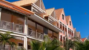 A multi-story hotel with balconies and a red-tiled roof. - Taino Beach Vacation Resort. (Freeport)