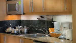 A kitchen with wooden cabinets, a microwave, a sink, and a coffee maker. - Taino Beach Vacation Resort. (Freeport)