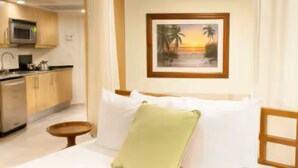 A hotel room with a bed, a small table, a microwave, and a kitchen area. - Taino Beach Vacation Resort. (Freeport)