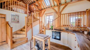 A rustic kitchen with wooden beams, a wooden staircase, and a view of the outdoors. - Airy Barn Conversion, Private Parking & Garden (Burrington)