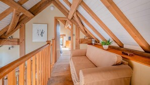 Un loft con vigas de madera a la vista, un sofá color beige y una mesita con una planta.