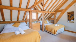 A room with two beds, wooden beams, a window, and a mirror on the wall. - Cosy Studio with Patio, Seating & Private Parking (Burrington)