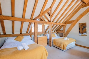 A room with two beds, wooden beams, a window, and a mirror on the wall. - Cosy Studio with Patio, Seating & Private Parking (Burrington)