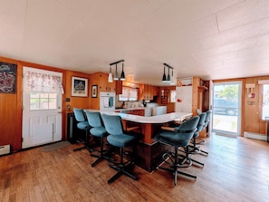 A kitchen with wooden cabinets, a white island with bar stools, and pendant lighting. - Cozy / River Front / Charm (Salida)