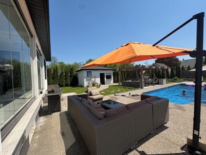 Ein Garten mit Schwimmbad, Gartenmöbeln und einer Pergola.