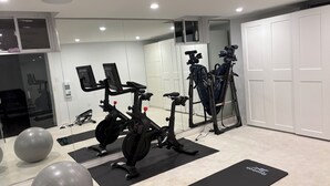 A home gym with exercise equipment, including a stationary bike, elliptical, and weight bench. - A vacation home from home (Hamilton)