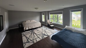 A bedroom with a bed, a chair, a window, and a view of a house. - A vacation home from home (Hamilton)