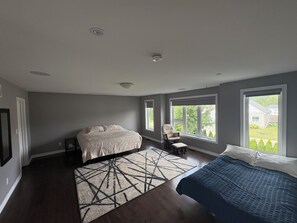 Ein Schlafzimmer mit Bett, Stuhl, Fenster und Blick auf ein Haus.