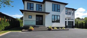 Une maison moderne à deux étages, dotée d’un toit plat, de grandes fenêtres et d’un porche à l’avant.