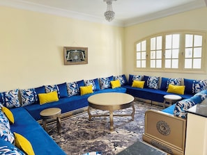 A room with a blue sofa, a round table, and a decorative cabinet.