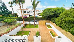 A courtyard with a checkered floor, white walls, and a view of a building in the background. - Villa plage David Bouznika (Bouznika)
