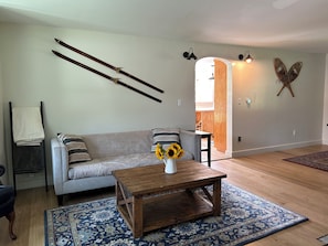 Un soggiorno con divano, tavolino, tappeto decorato, lampada a parete e elemento decorativo a muro.