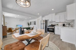 A modern kitchen with white cabinets, a stainless steel refrigerator, and a built-in oven. - Joshua Tree Oasis - 10 Min to Park - Hot Tub, Fire Pit & Stargazing (Joshua Tree)