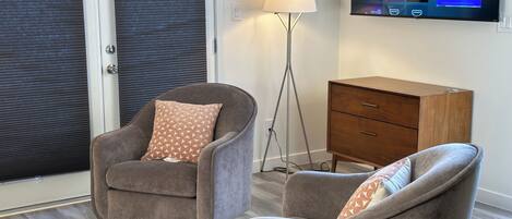 A living room with a sofa, a chair, a lamp, and a TV displaying a streaming service interface.