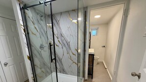 Moderni kylpyhuone, jossa on lasinen suihkuseinä, wc ja pesuallas.