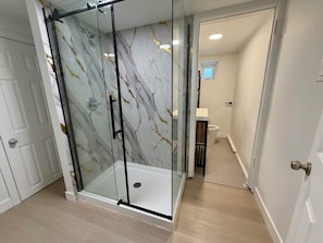 Ein modernes Badezimmer mit Duschkabine aus Glas, Toilette und Waschbecken.