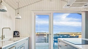 Et køkken med udsigt til en træterrasse og stole udenfor.