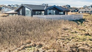Et moderne hus med skråt tag, store vinduer og en træterrasse.