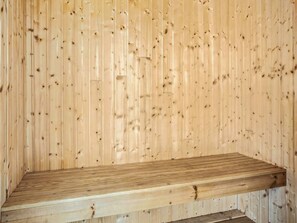 Un banco de madera apoyado en una pared revestida de tablones verticales.