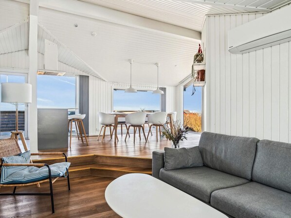 Ein modernes Interieur mit Essbereich, Sofa und großen Fenstern.