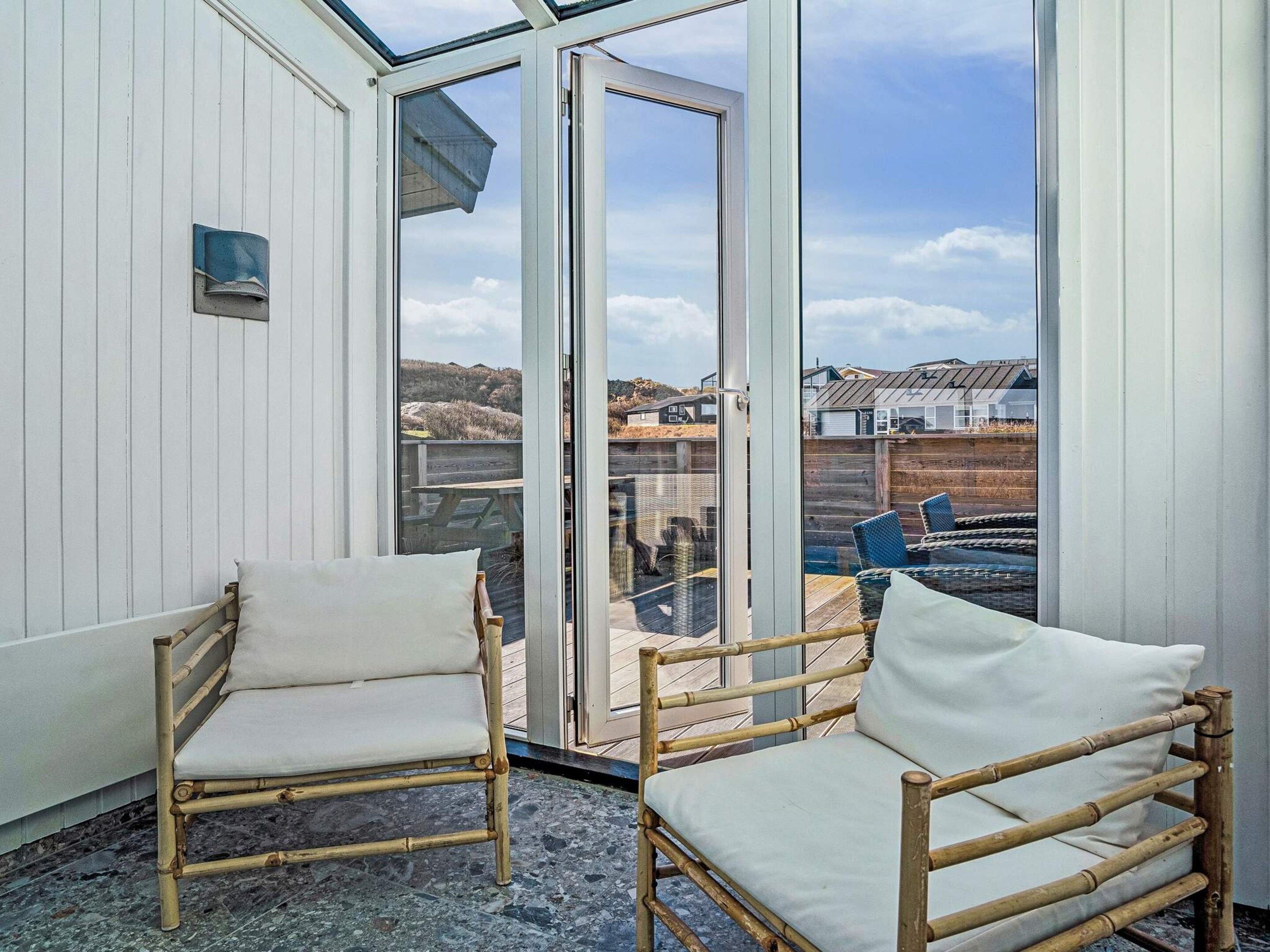Ein Zimmer mit zwei Korbstühlen und einer Glastür, die nach draußen führt.