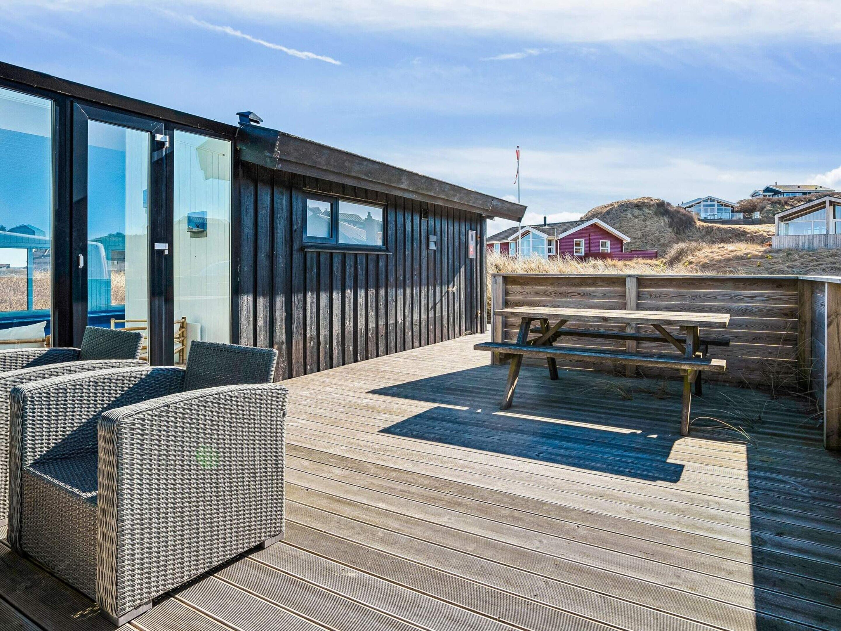 Une terrasse en bois avec des meubles en osier et une table de pique-nique.