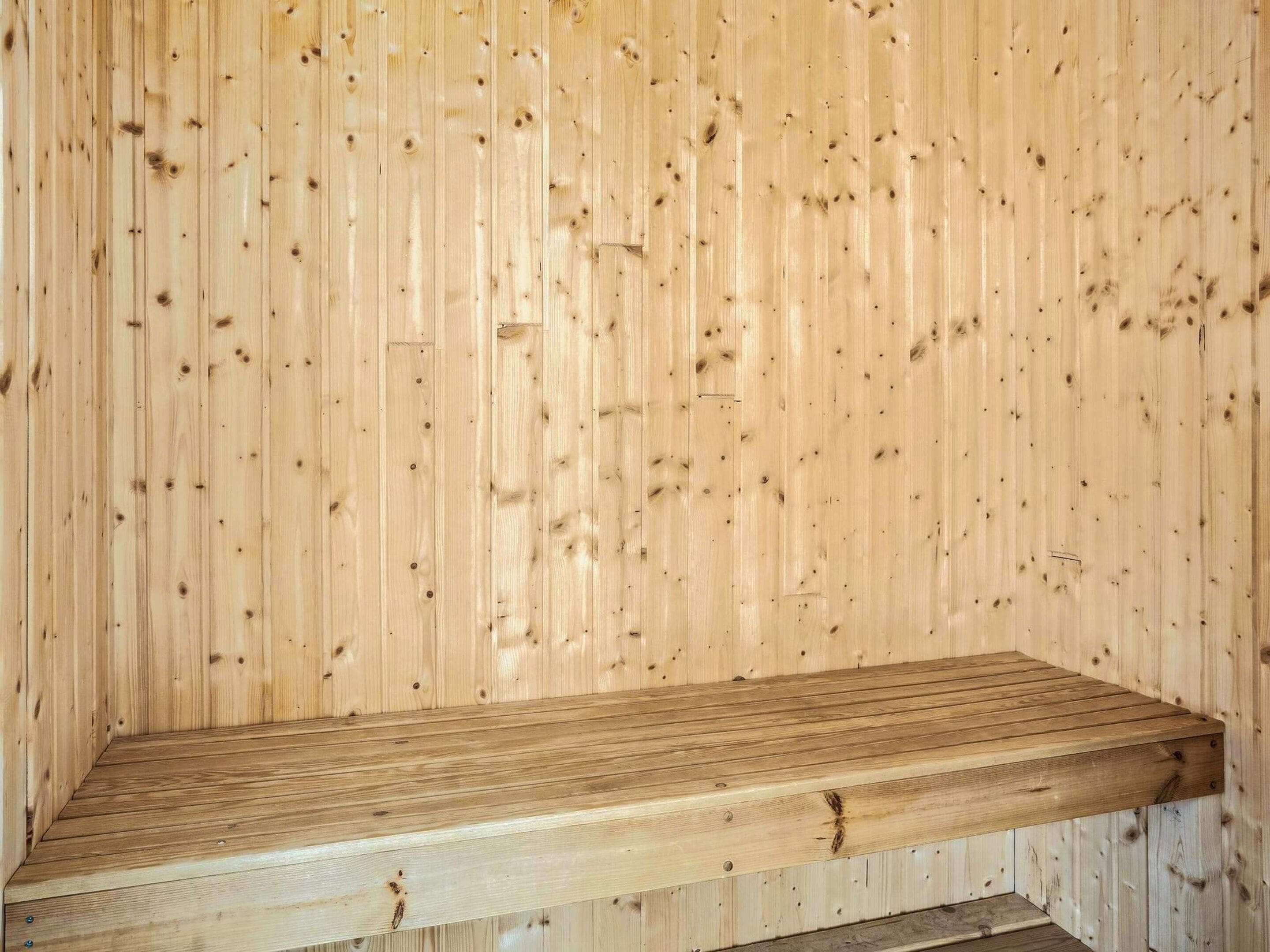 A wooden bench against a wooden wall.