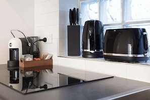 A modern kitchen with a coffee maker, a toaster, and a knife block. - The Den | Charming 1BR Glebe, Near Sydney Uni (Glebe)