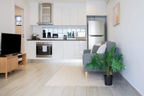 A modern kitchen with white cabinets, a built-in oven, and a stainless steel refrigerator. - Stylish 1BR Near CBD | WFH & Pet Friendly (Glebe)