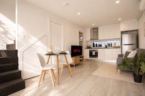 A modern apartment with a dining area, kitchen, living room, and staircase. - The Den | Charming 1BR Glebe, Near Sydney Uni (Glebe)