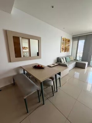 Ein modernes Wohnzimmer mit Esstisch, Bank, Sofa und einem großen Fenster.