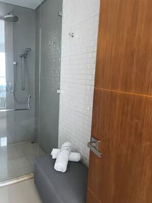 Ein modernes Badezimmer mit Duschkabine aus Glas, gefliesten Wänden und einer Holztür.