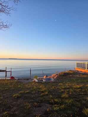 A beach view with a wooden deck, a surfboard, and a kayak.