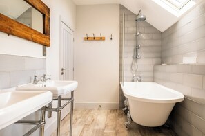 Un baño con dos lavamanos, una bañera, ducha y tragaluz.