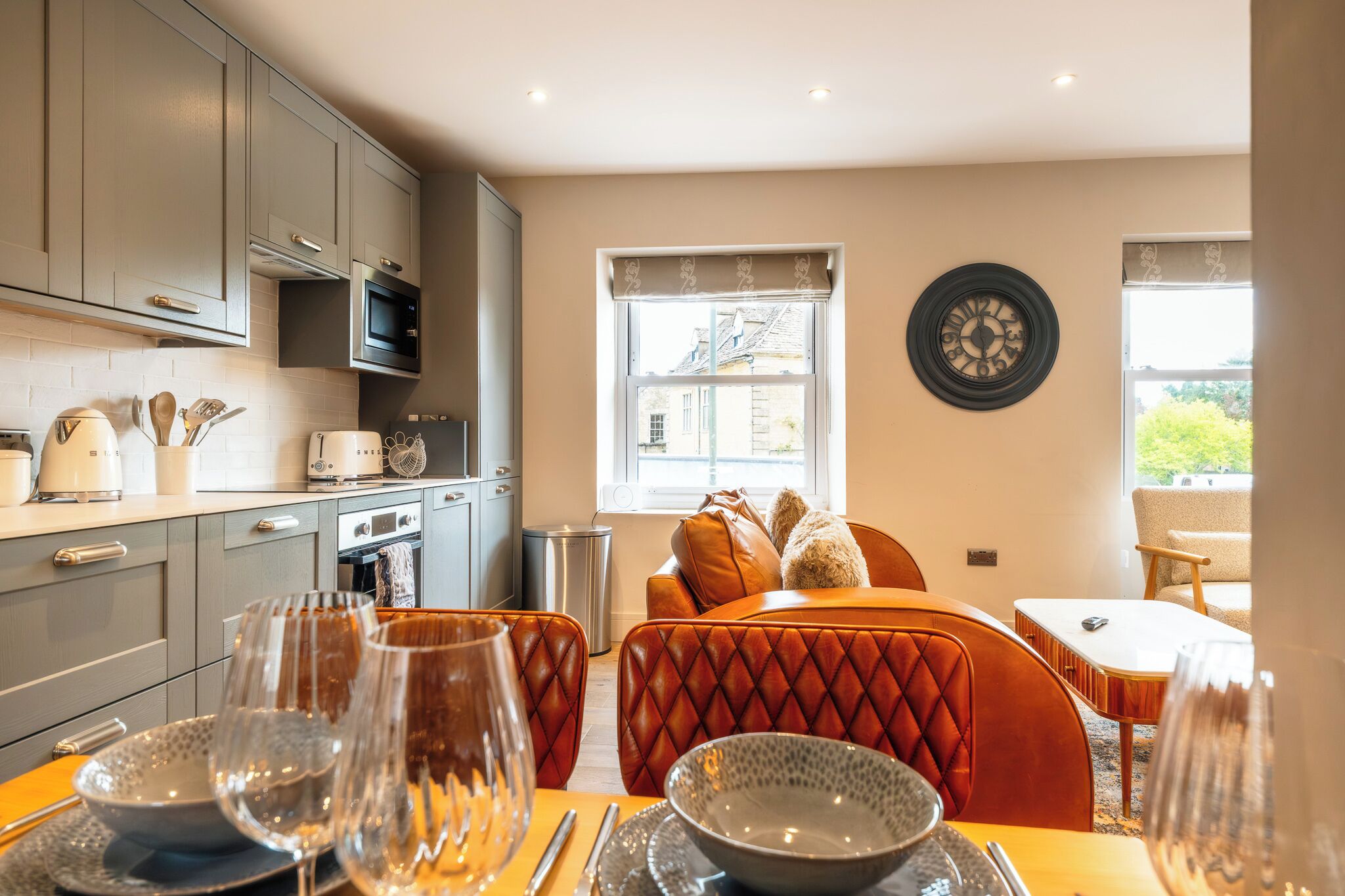 A modern kitchen with grey cabinets, a microwave, and a dining area with a table set for two.