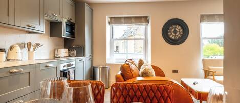 A modern kitchen with grey cabinets, a microwave, and a dining area with a table set for two.