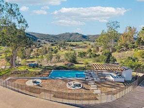 Um quintal com piscina, área de estar externa e um pergolado.