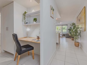 Ein modernes Interieur mit Schreibtisch, Stuhl, Regalen und Zimmerpflanzen.