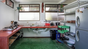 A compact kitchen with a sink, stove, and shelves for storage. - 2-bedroom A/C Apartment in Quepos (Quepos)