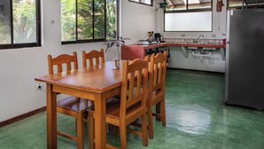 A dining area with a wooden table and chairs, a kitchen with a sink and stove, and a refrigerator. - 2-bedroom A/C Apartment in Quepos (Quepos)