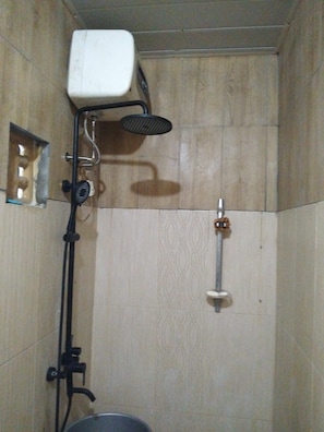 A shower with a handheld showerhead, a wall-mounted faucet, and a shower control panel.