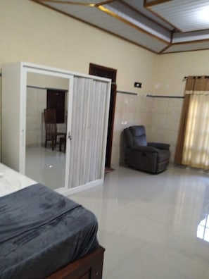 A bedroom with a bed, a sliding door, a chair, and a large window.