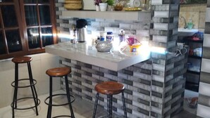 A kitchen with a central island, three stools, and a decorative backsplash. - Cozzy Ida Guest House (Sukawati)