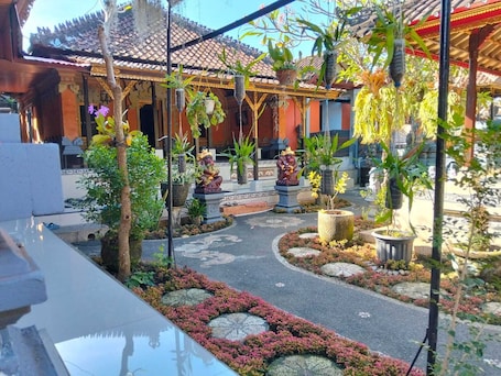A courtyard with a tiled roof, potted plants, and statues.. Cozzy Ida Guest House