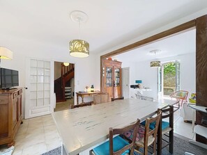A spacious dining area with a large table, chairs, and a television on a wooden cabinet. - QUIBERON - 4 room villa - 90m2 - City center (QUIBERON)